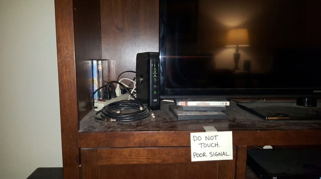 Roteador Wi-Fi escondido dentro de um rack de televisão e cercado por metal, mostrando o erro de bloquear as ondas de rádio do aparelho.