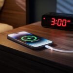 Celular moderno conectado ao cabo do carregador em cima da mesa de cabeceira do quarto durante a madrugada.