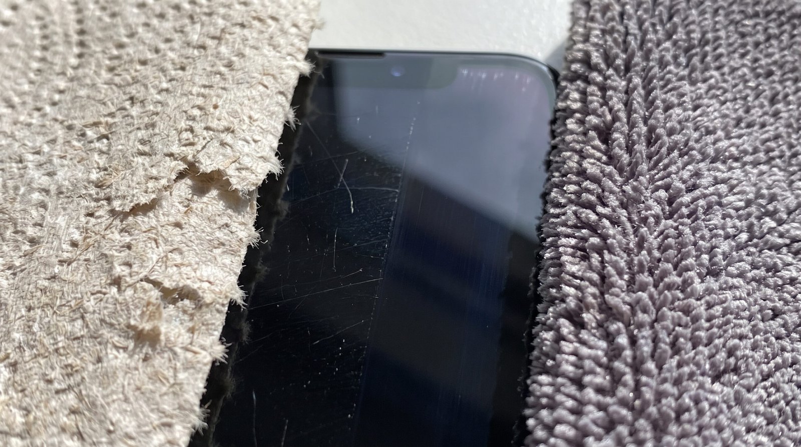 Fotografia macro comparando a textura áspera e abrasiva de um papel toalha contra a textura segura, macia e premium de um pano de microfibra para limpar telas.