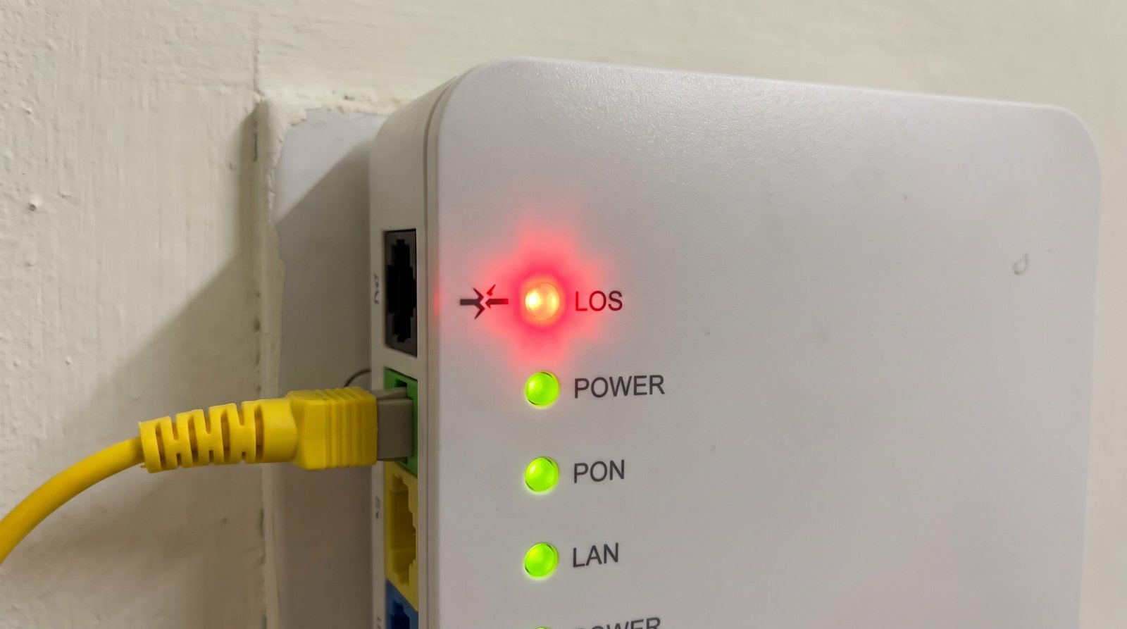 Painel de um modem de fibra óptica mostrando a luz vermelha de alerta LOS piscando de forma intensa, indicando rompimento do cabo da operadora.