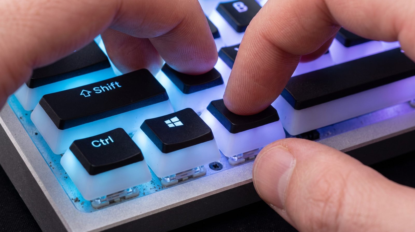 Visão detalhada de mãos pressionando as teclas Windows, Ctrl, Shift e B ao mesmo tempo no teclado do computador.