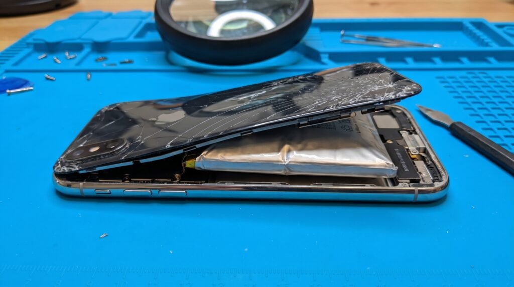 Visão lateral de um celular com a tampa traseira de vidro estufada, descolando devido ao inchaço perigoso da bateria interna.