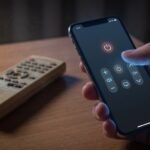 mão de um usuário na sala escura segurando um smartphone iluminado com interface limpa de controle remoto digital