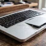 notebook prata na mesa, evidenciando o teclado deformado e o chassi estufado para cima com força