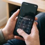 Usuário digitando código de diagnóstico no teclado do celular Android para verificar a saúde da bateria.
